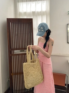 Gros plan détaillé sur la texture tressée évidée du grand sac fourre-tout en paille beige