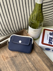 Detail of navy blue canvas mini storage pouch with contrast stitching on a wooden tray