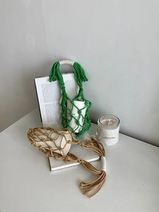 Détail du porte-bouteille en filet fait main avec pompons et poignée en cordelette