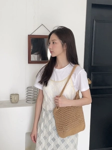 Detail of a brown handmade crochet hollow tote bag worn with a white vintage knitted dress
