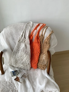Three multi-colored handmade woven shoulder bags displayed on a wooden chair