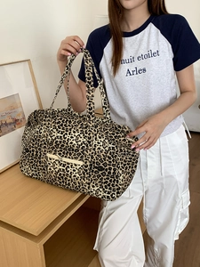 Close-up of leopard print canvas tote bag featuring double handles and front zipper pocket