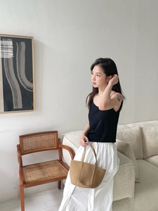 Close-up of a brown woven straw tote bag paired with a minimalist summer outfit