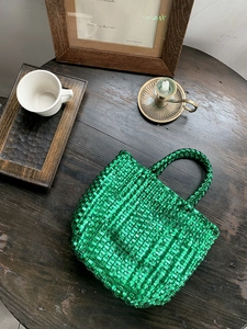 Close-up of bright green woven tote bag on a vintage wooden table with decor