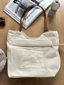 Detailed top view of a canvas tote bag with crochet trim and brown leather shoulder straps