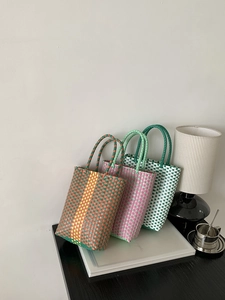 Detailed view of colorful PVC handmade woven handbags with durable dual handles