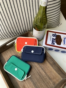 Three-color mini canvas storage pouches in a wooden tray showing snap pockets and zippers