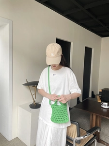 Detail of a bright green hand-woven cotton crossbody bag in a minimalist summer outfit