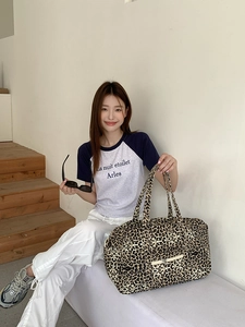 Detailed side view of leopard print tote bag with wide handles and front zipper pocket