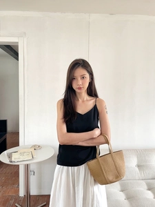Minimalist brown woven straw tote bag paired with a black tank top and white skirt