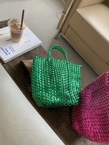 Close-up of metallic green woven handbag with checkered texture on vintage wood desk