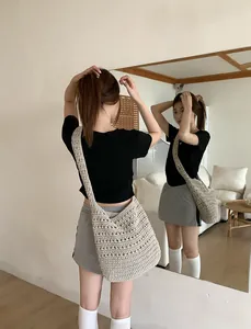 Mirror selfie showing the beige crochet tote bag with wide shoulder strap worn by a model
