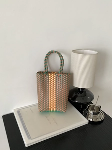 Detail of a handmade PVC woven tote bag with a retro countryside aesthetic and dual handles