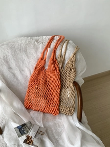 Detail of hand-woven hollow mesh tote bags in bright orange and natural beige cotton rope