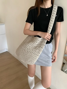 Detailed shot of an oversized beige woven cotton shoulder bag worn by a model