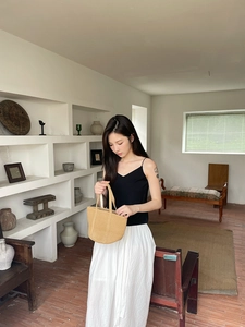 Minimalist straw woven tote bag shown in a lifestyle scene with a summer outfit