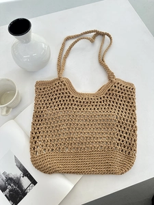 Close-up of khaki hollow crochet woven tote bag with handle on minimalist desk setup