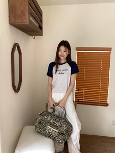 Close-up of leopard print canvas tote bag with front zipper pocket held by a model