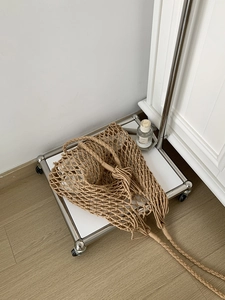 Detail of handmade woven cotton shoulder bag with long fringe tassels in natural beige tone