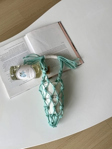 Détail du porte-bouteille en macramé vert menthe fait main avec design ajouré