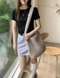 Detail of hand-woven cotton crochet tote bag in beige shown in an indoor lifestyle scene