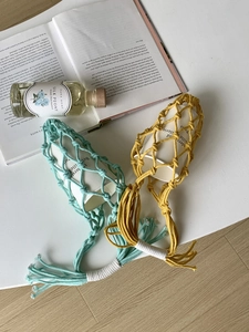 Détail de porte-bouteilles en macramé tissé main vert menthe et jaune moutarde à franges