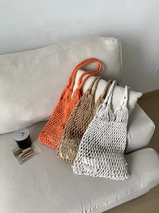 Close-up of handmade macrame hollow net bags in orange, khaki, and white cotton rope