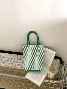 Detail of green and white checkered woven tote bag with durable PVC handles