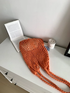 Close-up of orange handmade woven cotton tote bag with mesh hollow pattern for beach vacations