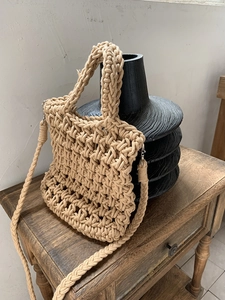 Close-up of beige hand-woven crochet bag with thick texture on a ceramic vase