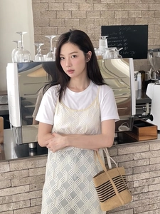 Detailed texture of white crochet hollow dress and woven straw tote bag in cafe setting