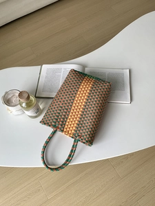 Detail of a handmade tricolor woven PVC tote bag with vibrant summer stripes and texture
