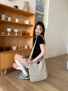 Close-up of beige crochet tote bag with hollow mesh design in a cozy interior setting