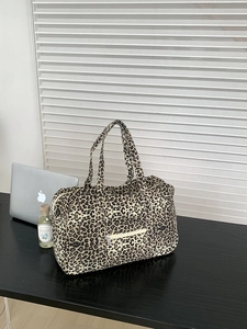 Detail of leopard print canvas tote bag featuring front zipper pocket and sturdy top handles