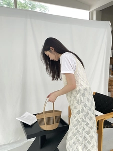 Straw tote bag with black stripes and crochet knit cardigan shown on a model in a studio
