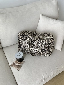 Detail of leopard print canvas tote bag with cream wide straps and secure zipper closure