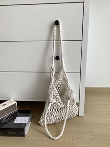Detail of white macramé handmade cotton woven tote bag hanging in a minimalist home setting