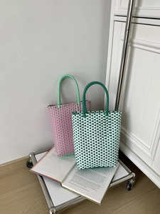 Detail of colorful woven PVC handbags on a silver trolley with artistic lifestyle props