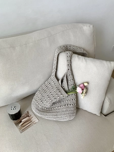 Close-up of beige crochet hobo tote bag with hollow woven texture on a soft sofa