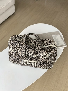 Detailed view of leopard print canvas travel bag with sturdy handles and side zipper pocket