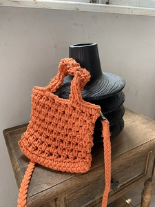 Detailed view of an orange hand-woven crochet crossbody bag with sturdy metal hooks