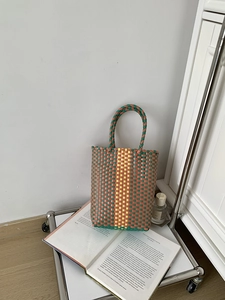 Detail of woven PVC beach bag with geometric patterns placed on a photography book