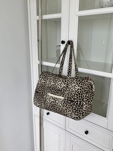 Detail of leopard print canvas tote bag with front zipper pocket hanging on a white cabinet