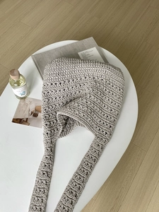 Detail shot of beige crochet tote bag showing woven texture on a white coffee table