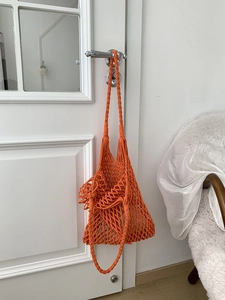 Detail of orange woven cotton shoulder bag featuring intricate diamond mesh hollow pattern