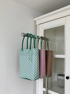 Detailed view of handmade PVC woven bags in green, pink, and brown grid patterns