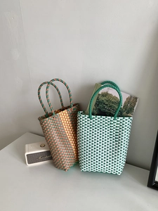 Detail shot of handcrafted PVC woven tote bags in orange and green contrast textures
