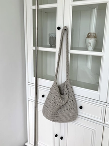Close-up of light gray cotton knit tote bag with mesh texture on a cabinet handle