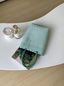 Detailed top view of a green and white checkered woven tote bag filled with books