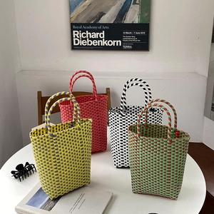 Detail of colorful hand-woven PVC baskets in diverse color block patterns on a table